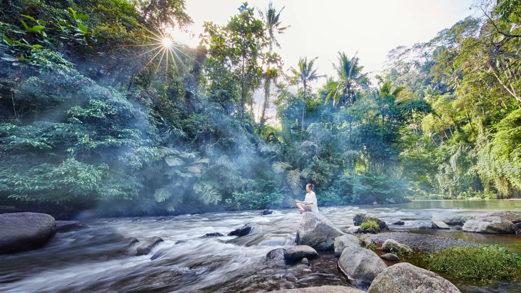 Guest meditating beside the Ayung River in the COMO Shambhala Estate jungle