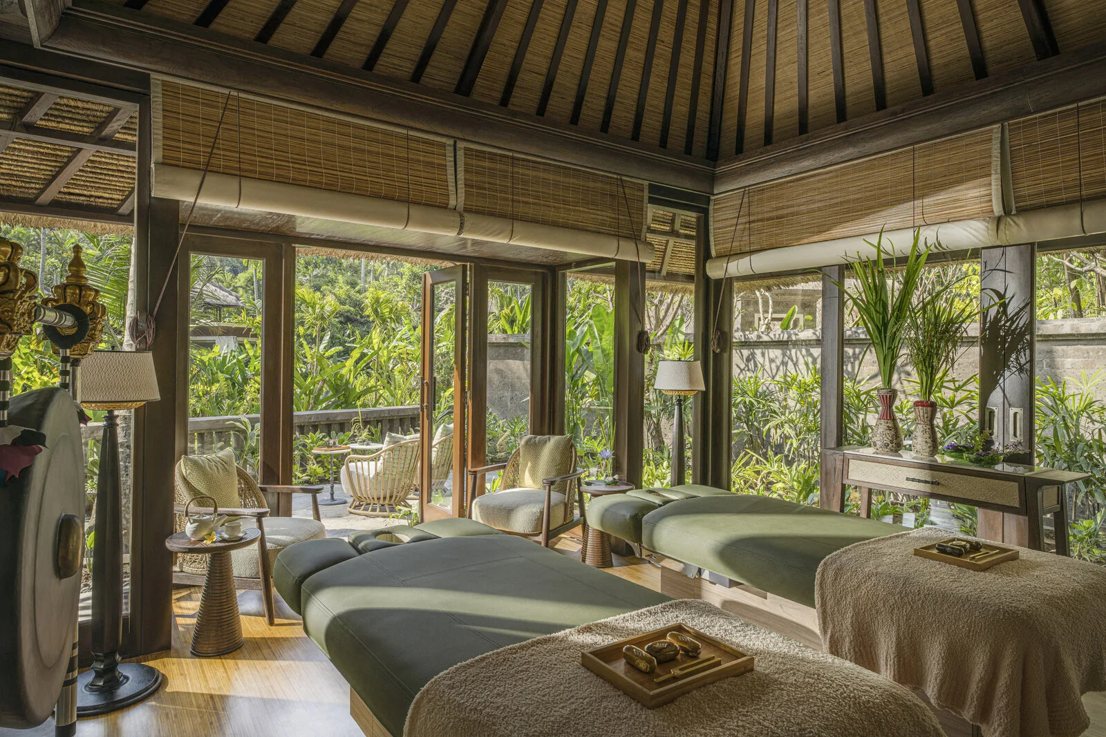 Spa treatment room with two massage tables and lush garden views