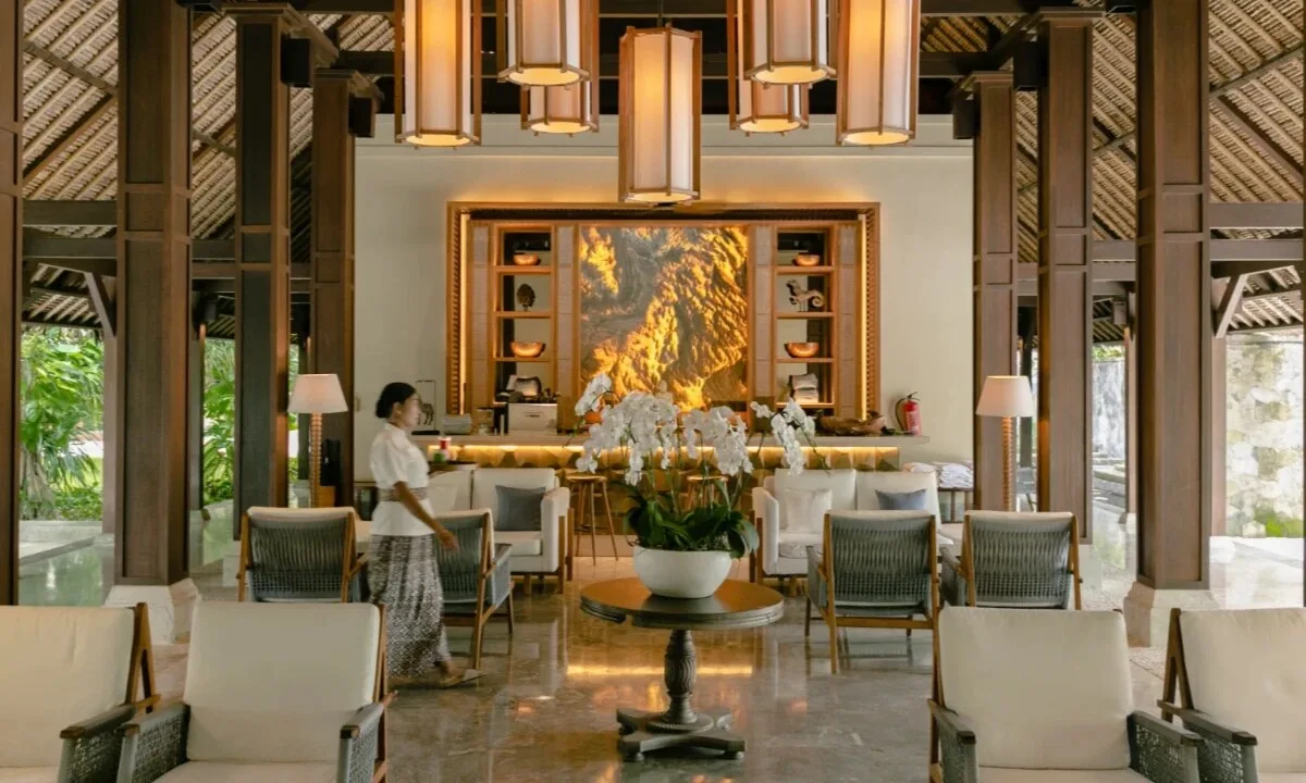Open-air hotel lobby with rattan lanterns, white orchids and garden views