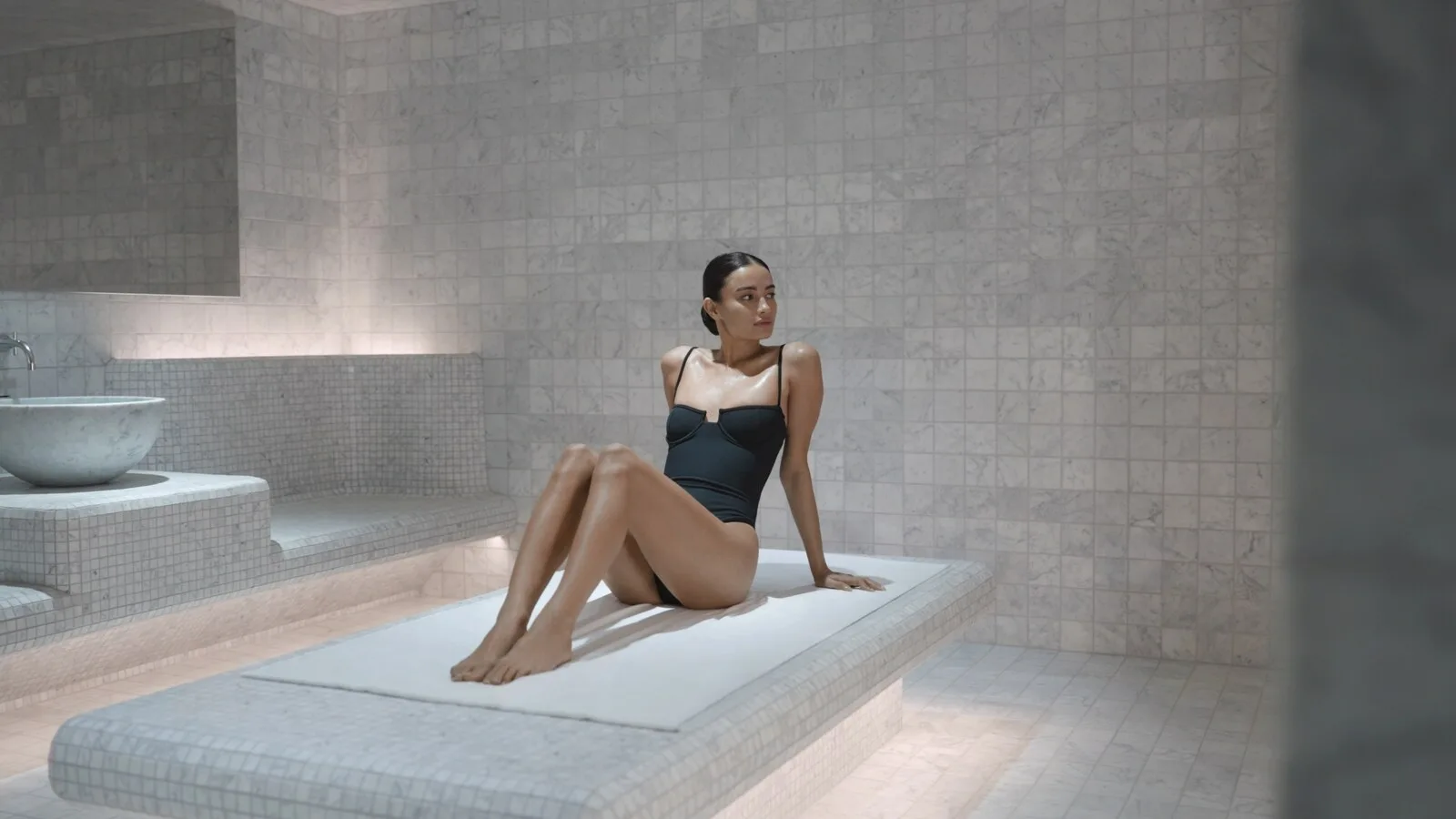 Woman seated in a pale tiled hammam at Waldorf Astoria New York